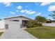 View of a gray single-story home with palm trees and manicured lawn, enhanced by a dolphin sculpture at 13704 Evelane Dr, Hudson, FL 34667