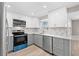 Modern kitchen featuring sleek stainless steel appliances, white cabinets, and stylish gray backsplash at 13704 Evelane Dr, Hudson, FL 34667