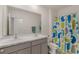 Well-lit bathroom featuring a dual sink vanity with a stylish countertop and a whale-themed shower curtain at 15959 Tuscany Hillside Rd, Odessa, FL 33556