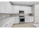 Well-equipped kitchen with white cabinets, gray backsplash, and modern stainless steel appliances at 1770 Pepper Grass Dr, North Port, FL 34289