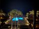 Night view of the illuminated community pool surrounded by palm trees at 18304 Gulf Blvd # 309, Redington Shores, FL 33708