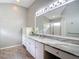Bathroom featuring long vanity with white cabinets and marble countertop, a large mirror, and natural light at 19227 Garden Quilt Cir, Lutz, FL 33558