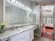 Bathroom featuring double vanity, marble countertop, bright lighting, and access to the bedroom at 19227 Garden Quilt Cir, Lutz, FL 33558