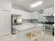 Well-lit kitchen boasts stainless steel appliances, white cabinets, granite counters, and an island with seating at 19227 Garden Quilt Cir, Lutz, FL 33558