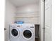Bright laundry room with white washer and dryer, wire shelves and motivational wall art at 19227 Garden Quilt Cir, Lutz, FL 33558
