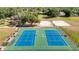 Aerial view of community tennis and sand volleyball courts, surrounded by trees at 19227 Garden Quilt Cir, Lutz, FL 33558
