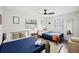 Bedroom featuring two twin beds with blue bedding, neutral walls, ceiling fan, and a large window at 2250 64Th N St, St Petersburg, FL 33710
