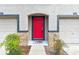 Close-up of a vibrant red front door framed by stone accents, flanked by garage doors at 2547 Lexington Oak Dr, Brandon, FL 33511