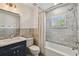 Bathroom features a tub shower with marble tiling, and a vanity with navy cabinets at 3008 S Church Ave, Tampa, FL 33629