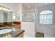 This bathroom features a tub, shower, granite counters and wooden cabinetry, with a bright window view at 316 Crystal Goblet Ct, Valrico, FL 33594
