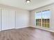 Clean and bright bedroom featuring a large window and wood flooring with neutral paint color at 3434 E Keysville Rd, Lithia, FL 33547