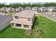 An aerial view of a tan two-story home with a lush green lawn and tropical landscaping in a suburban neighborhood at 3488 Great Banyan Way, Wesley Chapel, FL 33543