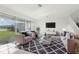 Bright living room featuring neutral furnishings, a textured rug, and large windows with views of the backyard and lake at 3488 Great Banyan Way, Wesley Chapel, FL 33543