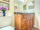 Bathroom with a granite countertop, wooden cabinets, vanity mirror, and toilet at 503 Finsbury Cir # A, Sun City Center, FL 33573