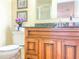 Bathroom featuring a granite countertop, wooden cabinets, vanity mirror, and a toilet at 503 Finsbury Cir # A, Sun City Center, FL 33573