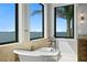 Luxury bathroom featuring a soaking tub, large windows, and waterfront views at 5939 Bayview S Cir, Gulfport, FL 33707