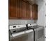 Laundry room with stainless steel washer and dryer units, and dark wood cabinets above at 5939 Bayview S Cir, Gulfport, FL 33707