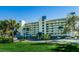 Low-rise condominium with a lush green lawn and palm trees, with ample parking underneath at 7882 Sailboat Key S Blvd # 401, South Pasadena, FL 33707