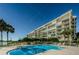 Bright outdoor pool surrounded by lush tropical landscaping, with a multi-story building in the background at 7882 Sailboat Key S Blvd # 401, South Pasadena, FL 33707