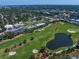 Aerial view featuring real estate adjacent to a manicured golf course, tennis court, and pond at 919 Osceola Rd # 202, Belleair, FL 33756