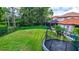 Large backyard featuring a well-maintained lawn, mature trees, a trampoline, and a view of the pool area at 11624 Bristol Chase Dr, Tampa, FL 33626
