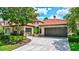 Beautiful home exterior featuring a red tile roof, lush landscaping and three-car garage at 11624 Bristol Chase Dr, Tampa, FL 33626