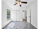 Bright bedroom showcasing large windows, ceiling fan, gray tile, and a closet with louvered doors at 12062 Stone Crossing Cir, Tampa, FL 33635