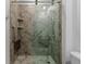 Modern walk-in shower featuring gray marble tile, glass doors, and a built-in seat and shelving at 13227 Waterleaf Garden Cir, Riverview, FL 33579