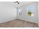Sunny bedroom featuring wood-look laminate flooring, a ceiling fan and two windows at 13227 Waterleaf Garden Cir, Riverview, FL 33579