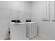 A bright laundry room features a white washer and dryer, wire shelving, and a neutral tiled floor at 13227 Waterleaf Garden Cir, Riverview, FL 33579