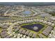 Expansive aerial view of a well-planned community featuring numerous homes, serene ponds with fountains, and lush landscaping at 13227 Waterleaf Garden Cir, Riverview, FL 33579