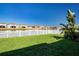 A spacious backyard with a white fence overlooking a tranquil lake and neighboring houses at 13651 Ashlar Slate Pl, Riverview, FL 33579