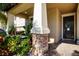 Inviting front porch featuring stone accents, lush plants, and a cozy swing for relaxing outdoors at 13651 Ashlar Slate Pl, Riverview, FL 33579
