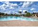 A beautiful pool with blue water, palm trees, lounge chairs and umbrellas on a sunny day with a few clouds at 13651 Ashlar Slate Pl, Riverview, FL 33579