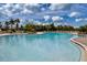 A large, luxurious, turquoise pool is surrounded by lounge chairs and green landscaping under a bright blue sky with white clouds at 13651 Ashlar Slate Pl, Riverview, FL 33579