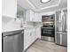 Modern kitchen with stainless steel appliances, white cabinets, and gray flooring at 13926 Helen Ave, Hudson, FL 34667