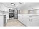 Bright modern kitchen features white cabinets, stainless steel appliances, island, and gray flooring at 13926 Helen Ave, Hudson, FL 34667