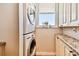 A laundry room features stacked washer and dryer and granite countertop workspace with storage cabinets beneath at 14900 Gulf Blvd # 212, Madeira Beach, FL 33708