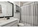 Bright bathroom with a white vanity, gray storage cabinet, and a shower with a striped curtain at 1499 Gopher Loop, Tarpon Springs, FL 34689