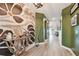 Stylish hallway featuring hardwood floors, with green painted walls, mural, and decorative lighting at 1499 Gopher Loop, Tarpon Springs, FL 34689