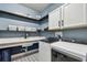 Well-organized laundry room with blue walls, white cabinets, a wash sink, and modern appliances at 1499 Gopher Loop, Tarpon Springs, FL 34689
