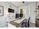 Home office with modern desk, dual monitors, stylish decor, and view into the kitchen at 1499 Gopher Loop, Tarpon Springs, FL 34689