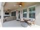 Relaxing covered patio with fan, comfortable seating, and a view of the fenced backyard at 1499 Gopher Loop, Tarpon Springs, FL 34689