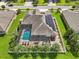 Aerial view of house with solar panels and a screen enclosed pool, surrounded by palm trees and green grass at 2417 Cumberland Cliff Dr, Ruskin, FL 33570
