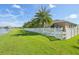 Expansive backyard with lush green grass, a white fence, offering privacy and a serene view of the adjacent lake at 2417 Cumberland Cliff Dr, Ruskin, FL 33570