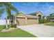 Charming home with a three-car garage, lush landscaping, a palm tree, and a well-maintained lawn at 2417 Cumberland Cliff Dr, Ruskin, FL 33570
