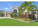 Beautiful home featuring a lush garden with vibrant plants and a grand arched entryway at 2417 Cumberland Cliff Dr, Ruskin, FL 33570