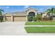 Well-manicured front lawn and landscaping leading up to a home with a three-car garage at 2417 Cumberland Cliff Dr, Ruskin, FL 33570