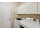 Laundry room with overhead cabinets, modern appliances and an electronic control panel on the wall at 2417 Cumberland Cliff Dr, Ruskin, FL 33570