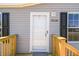 Up close front entry features wood porch, black framed windows and light grey colored siding at 25126 Huston St, Brooksville, FL 34601